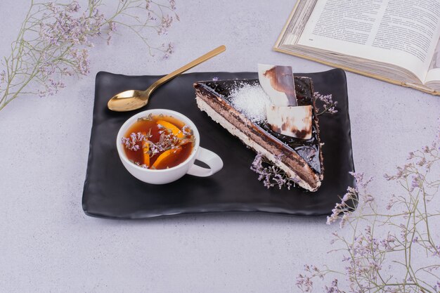 A slice of chocolate ganache cake with a cup of herbal tea.