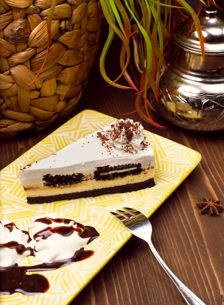 素朴な茶色の木のテーブルに対して皿にチョコレートバニラチーズケーキのスライス