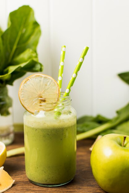 Slice of fruit near herbs and glass with cocktail and straws