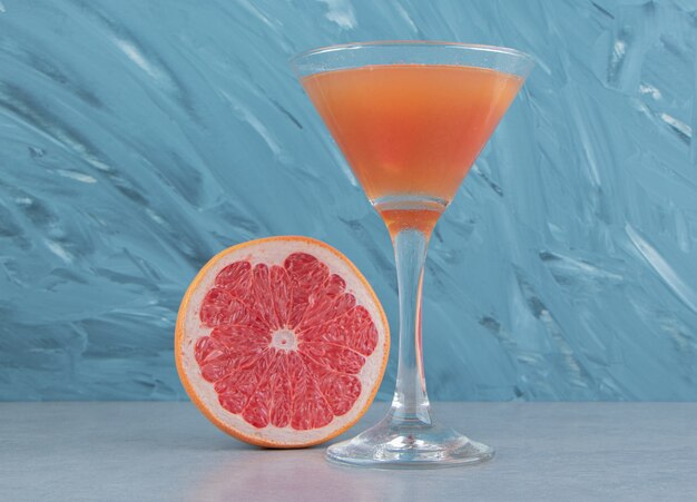 A slice of grapefruit and juice, on the blue background. High quality photo