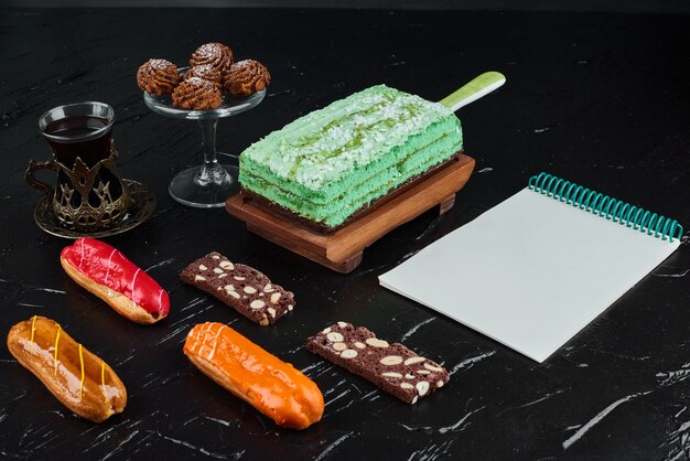 A slice of green cake with eclairs and recipe book.