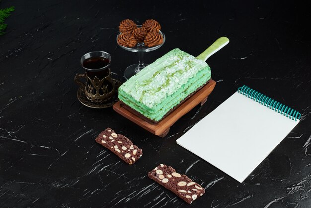 A slice of green cake with a recipe book. 