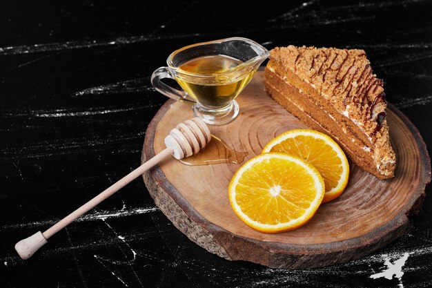 Кусочек медового торта с дольками апельсина и сиропом