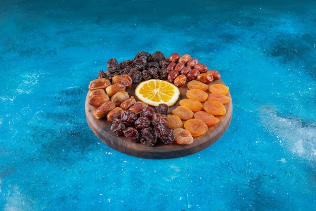 Free photo slice lemon and dried fruits on a board on the blue surface