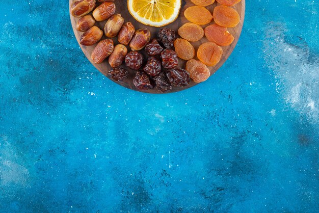 Slice lemon and dried fruits on a board , on the blue table. 