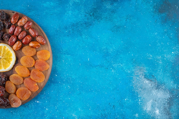 Slice lemon and dried fruits on a board , on the blue table. 