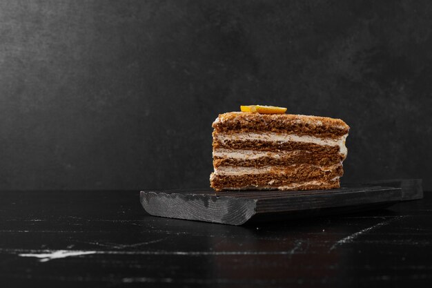 A slice of medovic cake on black stone.