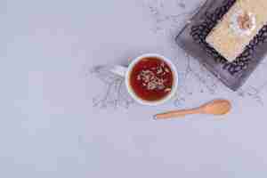 Free photo a slice of medovic cake with chocolate beans in a black platter with a cup of tea