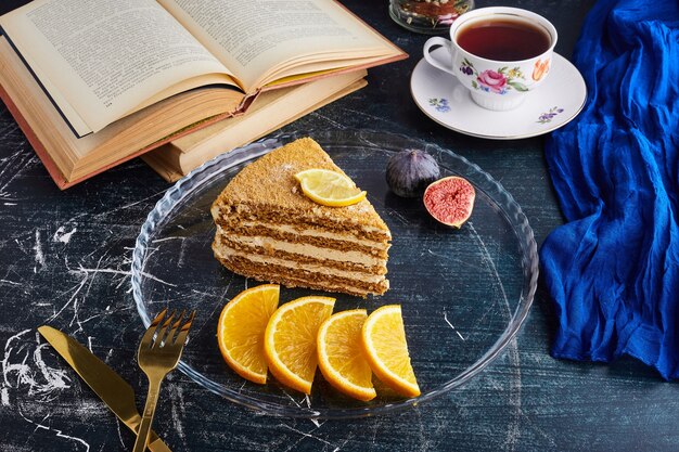 柑橘系の果物とお茶とメドビックケーキのスライス。