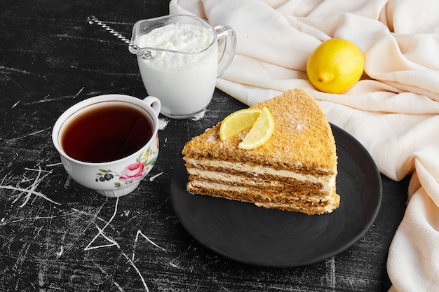 A slice of medovic cake with lemon, curd and a cup of tea. 