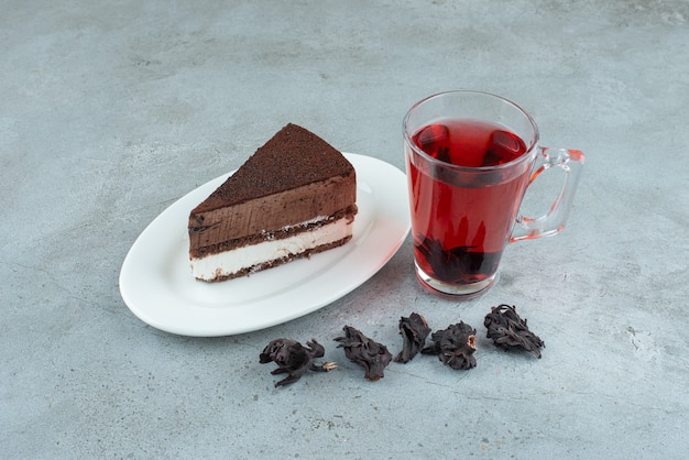 Бесплатное фото Кусочек торта и стакан чая на мраморной поверхности. фото высокого качества