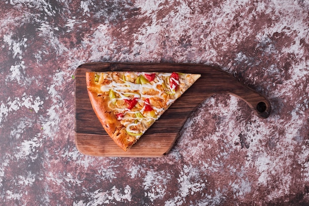 Кусок пиццы на деревянной доске, вид сверху