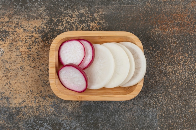 A slice of radishes in the bowl  on the marble surface