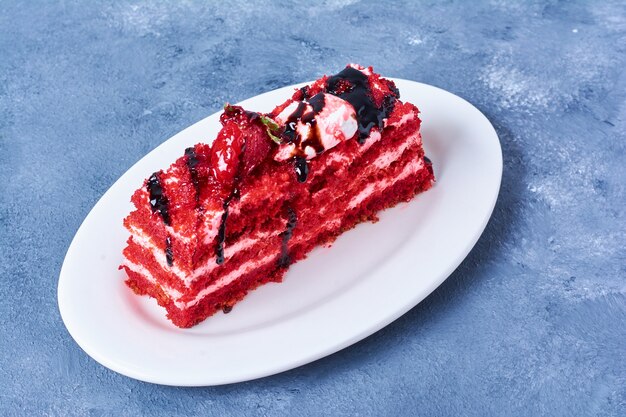 A slice of red velvet cake in a white plate.