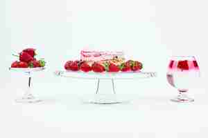 Free photo a slice of strawberry cheesecake with fruits and a glass of drink.