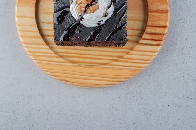 나무 접시에 크림과 함께 맛있는 초콜릿 브라우니 조각. 고품질 사진