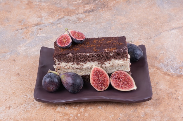 A slice of tiramisu with purple figs on the platter.