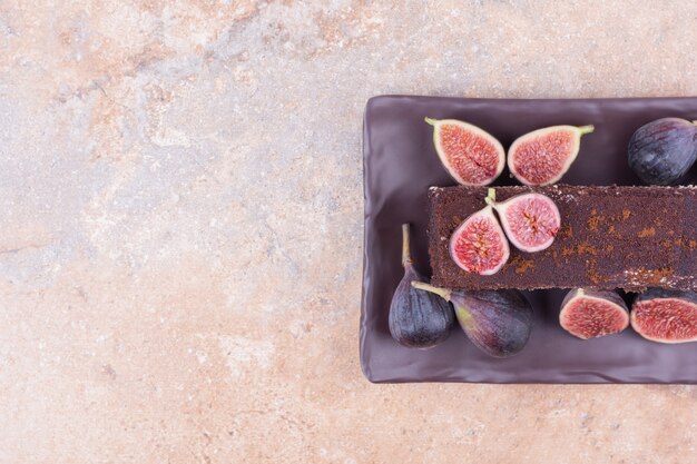 A slice of tiramisu with purple figs on the platter.