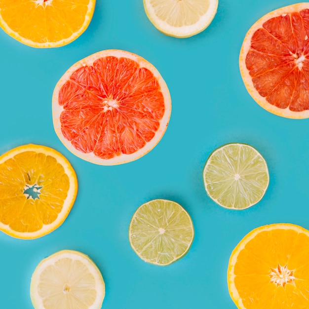 Slice of various citrus fruits on blue surface