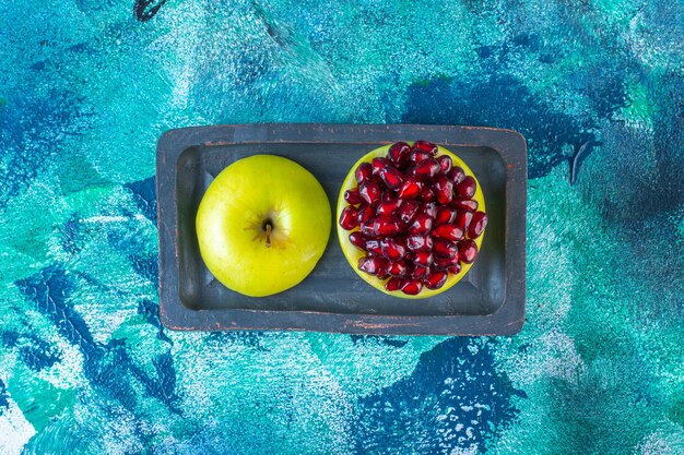 Sliced apple and pomegranate arils on a wooden plate 