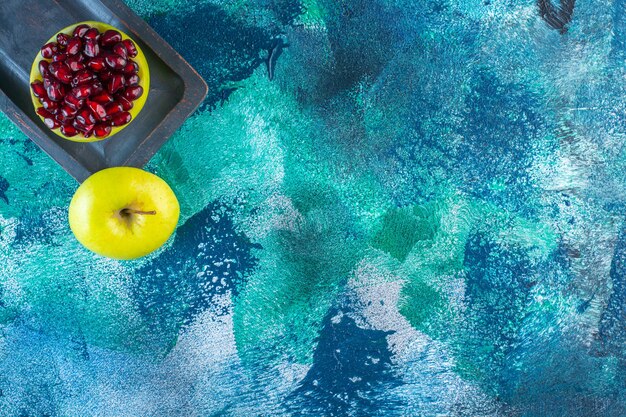 Sliced apple and pomegranate arils on a wooden plate 