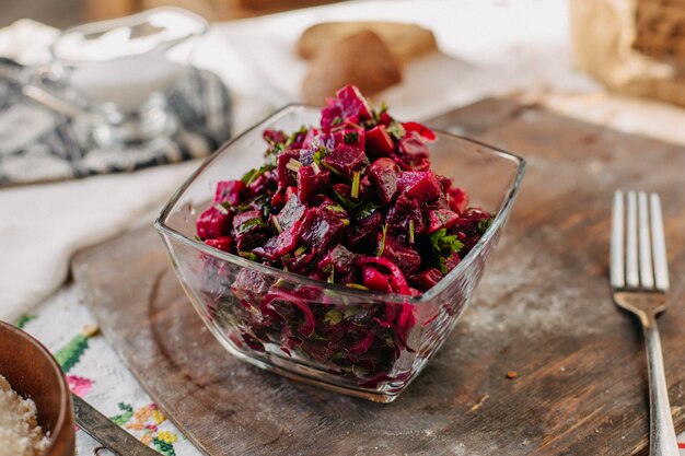 sliced beet salad salted with greens inside glass on brown wood rustic desk