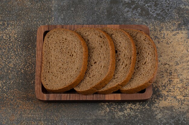 Sliced black bread on wooden plate