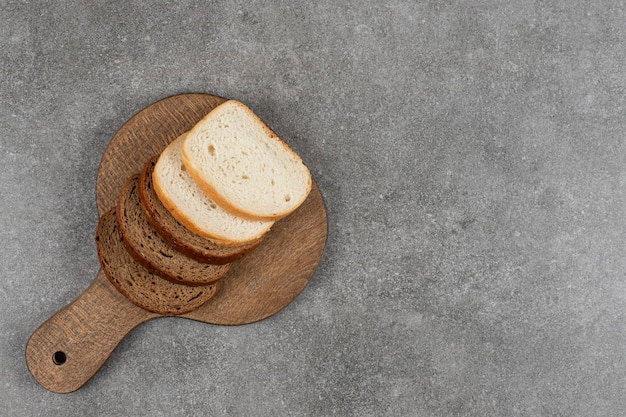 Нарезанный черный и белый хлеб на деревянной доске