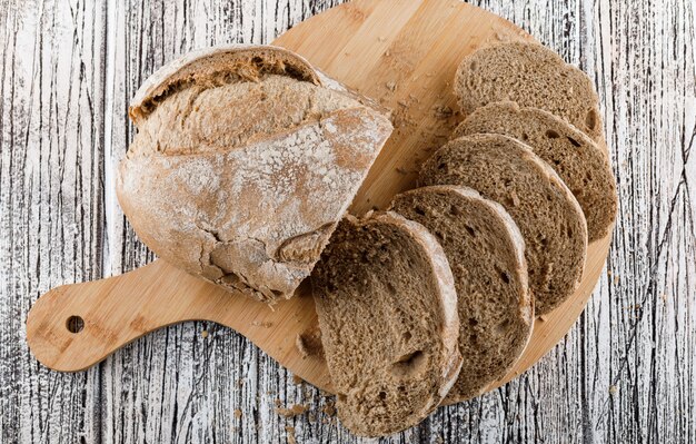 Free photo sliced bread in a on cutting board on a wooden surface. top view.