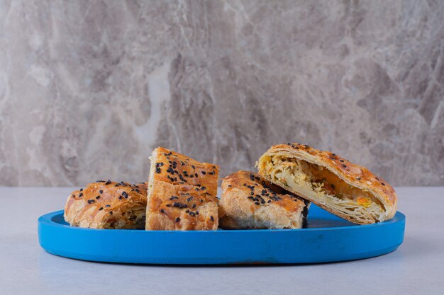 Нарезанный хлеб с кунжутом на деревянной тарелке на темной поверхности