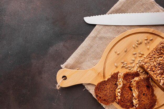 Sliced bread on wooden boar with seeds and knife