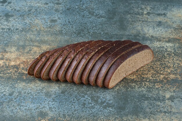大理石の背景にスライスした茶色のパン