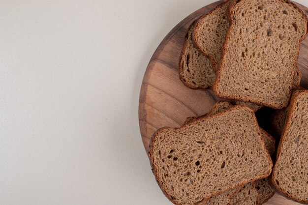 Нарезанный черный хлеб на деревянной тарелке. Фото высокого качества