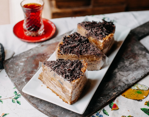 Foto gratuita torta marrone affettata squisita deliziosa cioccolata in polvere all'interno del piatto bianco con tè caldo