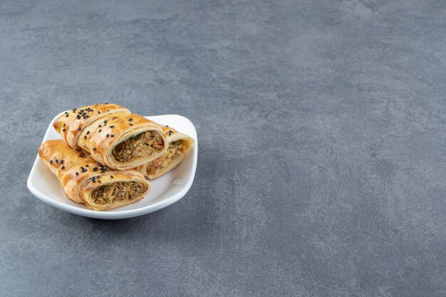 Sliced bun stuffed with meat on white plate.