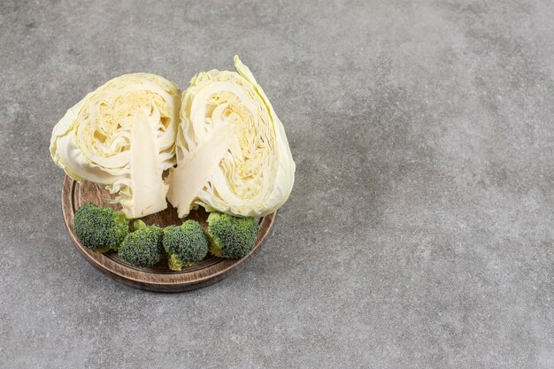 Sliced cabbage and broccoli on a board on a board, on the marble table. 