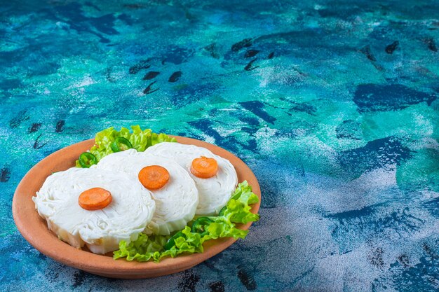 Sliced carrots, cabbage and lettuce leaves on a plate 