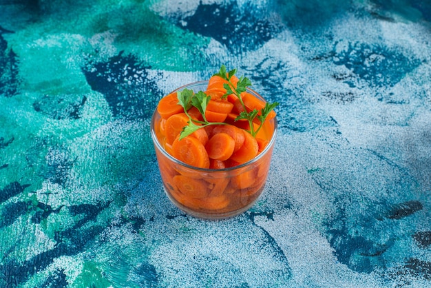 Sliced carrots in a glass , on the blue background. 
