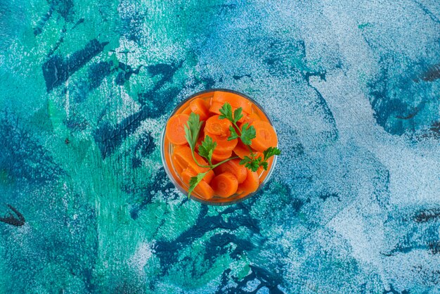 Free photo sliced carrots in a glass , on the blue background.