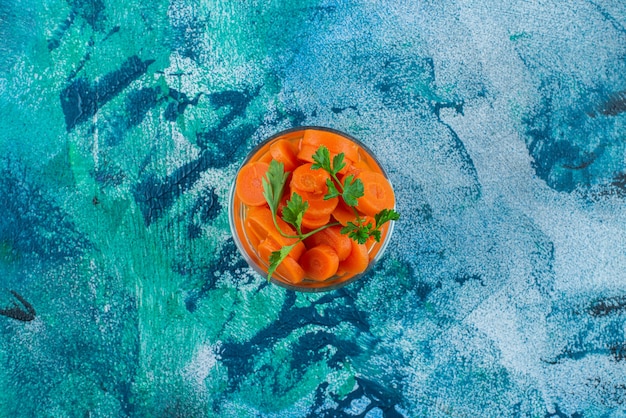 Sliced carrots in a glass , on the blue background. 