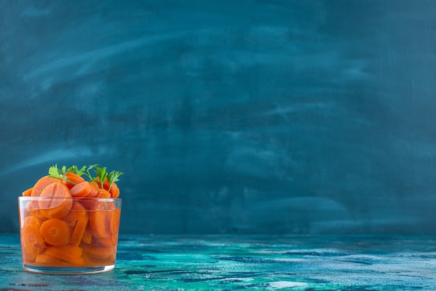 Foto gratuita carote affettate in un bicchiere, sul tavolo blu.