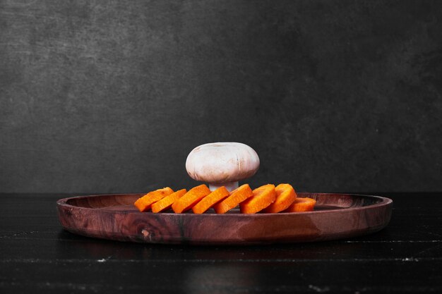 Нарезанная морковь и гриб на деревянной доске.