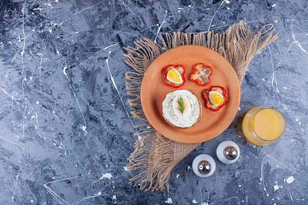 Sliced cheese bread and pepper on a plate next to a glass of juice , on the blue background.