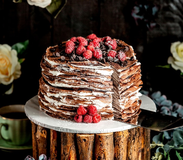 Sliced chocolate crepe cake topped with raspberries