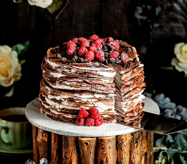 Sliced chocolate crepe cake topped with raspberries