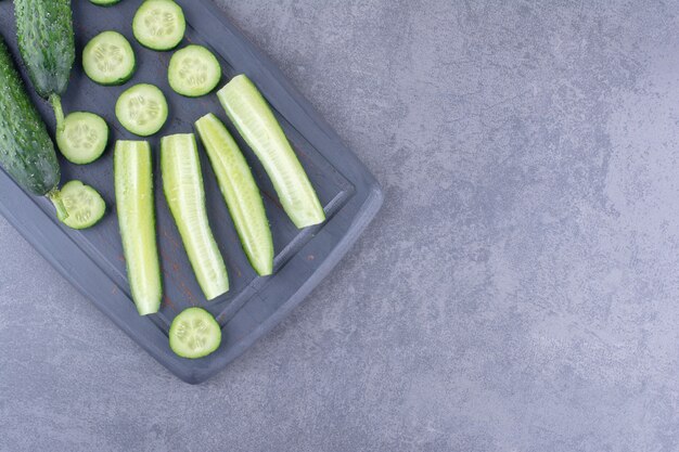 Sliced and chopped cucumbers on a wooden platter.