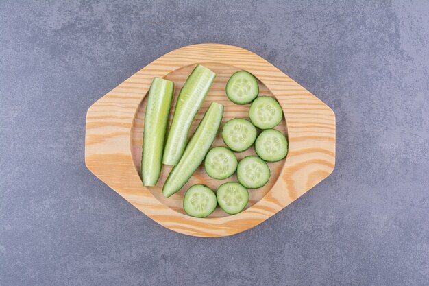Sliced and chopped cucumbers on a wooden platter.