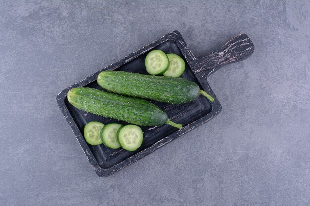 Sliced and chopped cucumbers on a wooden platter.