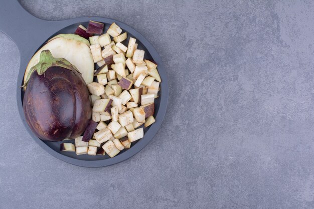 Sliced and chopped eggplants on a wooden platter.