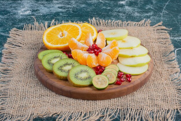 Sliced and chopped fruits salad in a platter on blue surface.